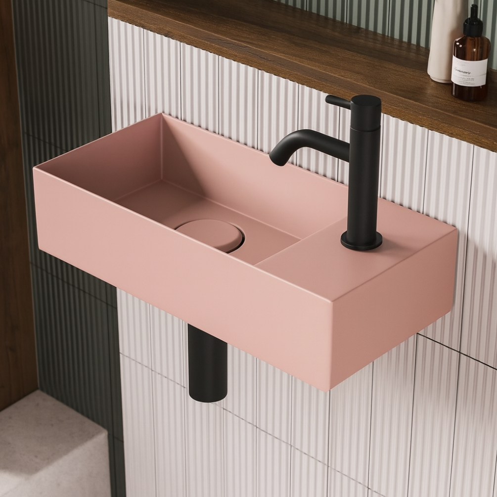 Lifestyle image of the Zero 3 450mm x 200mm Matt Pink Cloakroom Wall Mounted Basin installed on tiled walls with a black basin mixer